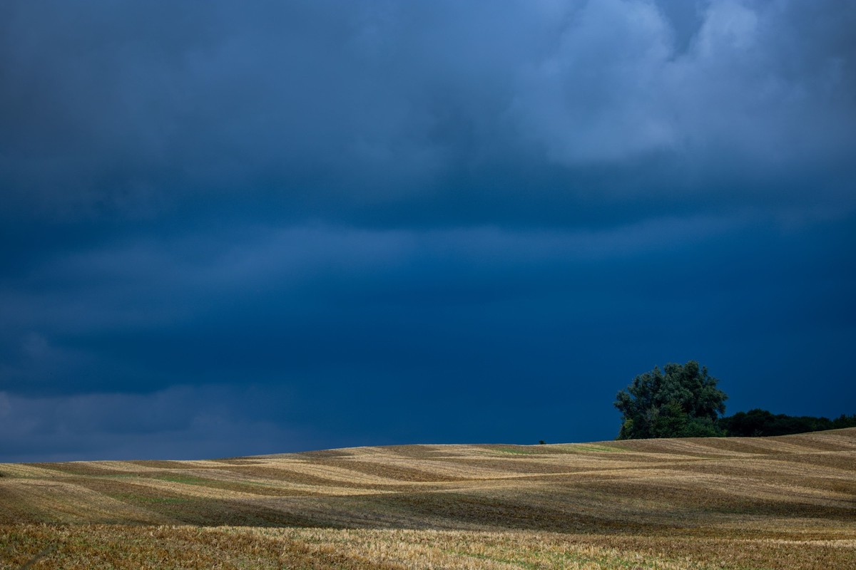 17.07.2025, Mecklenburg-Vorpommern, Dümmer: Dunkle Regenwolken verdunkeln den Himmel über einem abgeernteten Getreidefeld. Wechselhaft mit Sonne, kräftigen Regenschauern und Temperaturen um die 20 Gra ...