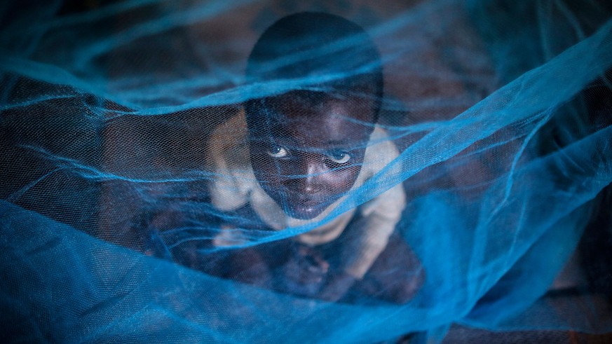 ARCHIV - 18.05.2015, Ruanda, Gashora: Ein Flüchtlingskind aus Burundi sitzt in Gashora, Ruanda, unter einem Moskitonetz. Die Weltgesundheitsorganisation (WHO) hat einen zweiten Malaria-Impfstoff für K ...