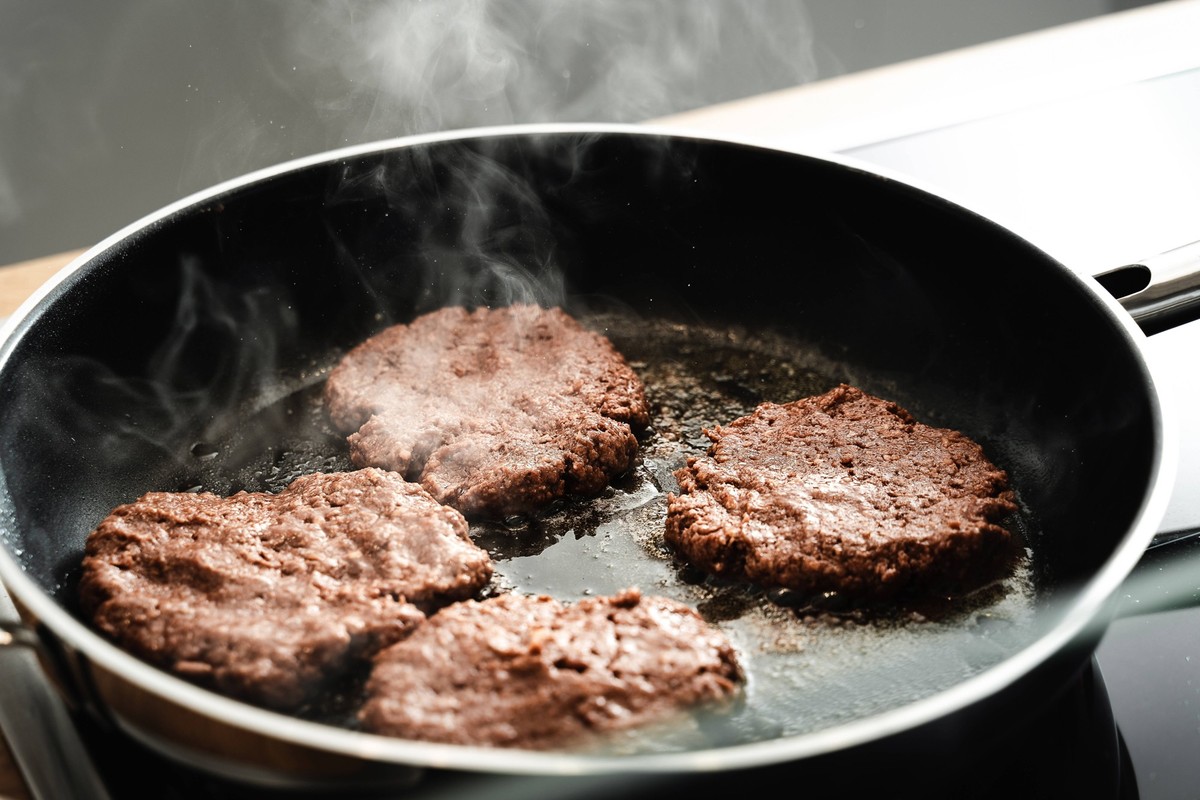 06 February 2022: Vegan hamburger patties made from pea protein, vegetable vegan meat replacement burger is fried in a hot pan with oil *** Vegane Hamburger Pattys aus Erbsenprotein, pflanzlich vegan  ...