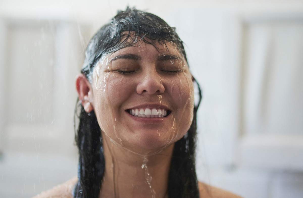 Woman, shower and happy in bathroom for hygiene, washing and water drops to refresh for skincare and relax. Young lady, smile and clean body for morning beauty treatment and healthy with self care