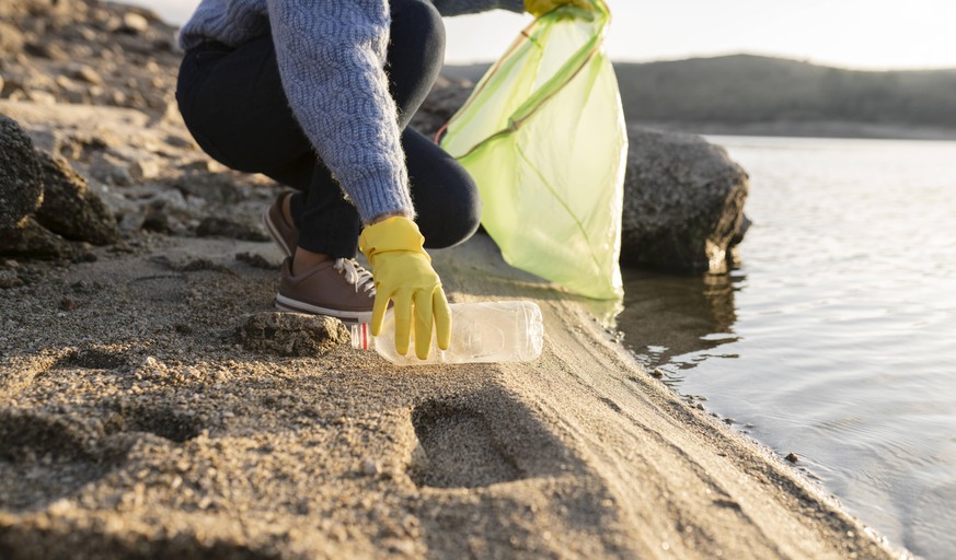 Woman picking up plastic bottle on beach by seashore model released, JCCMF05216