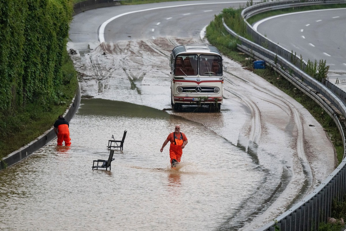03.06.2024, Baden-Württemberg, Ebersbach: Einsatzkräfte arbeiten auf der überfluteten Bundesstraße 10 in der Nähe einer geborstenen Lärmschutzwand. Foto: Marijan Murat/dpa +++ dpa-Bildfunk +++