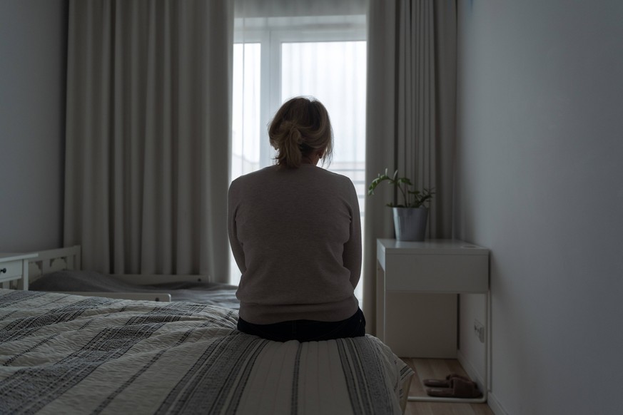 Mature woman sitting alone in the room, sad depressed person. Back view. mental health Mature woman sitting alone in the room, sad depressed person. Back view. mental health problemageing population.  ...
