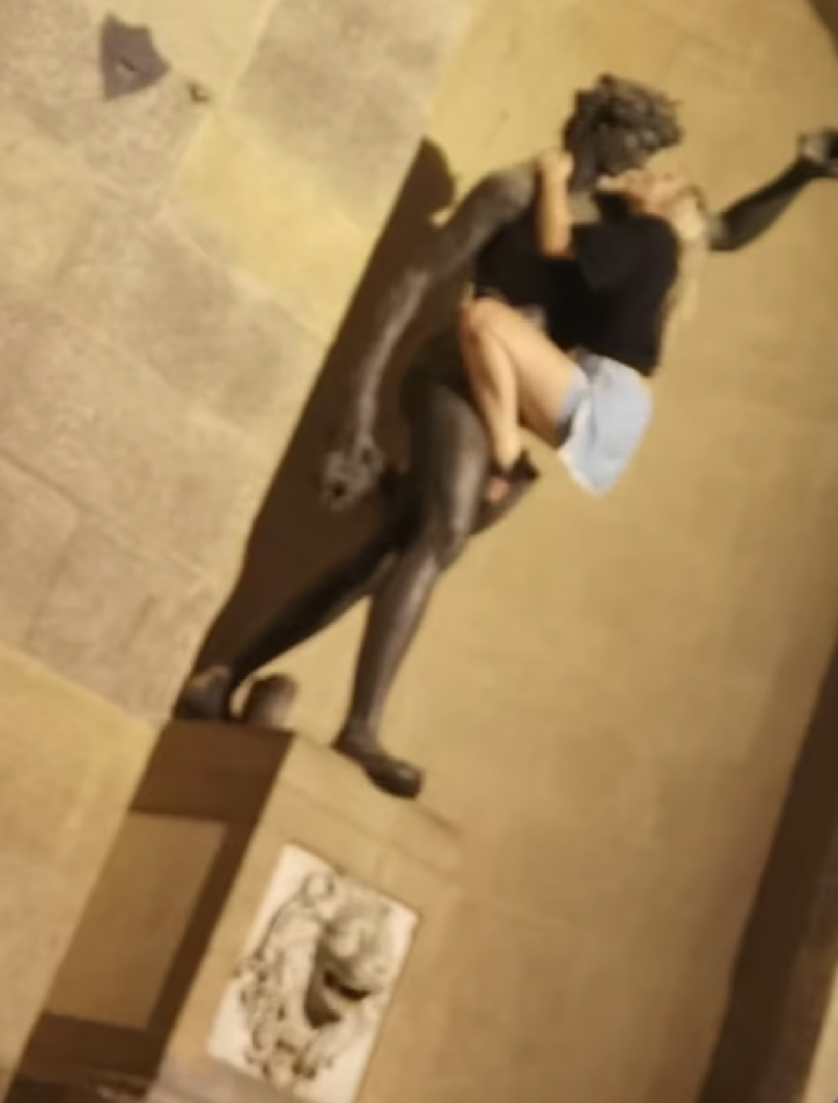 Die Touristin klettert auf die Bronze-Statue.