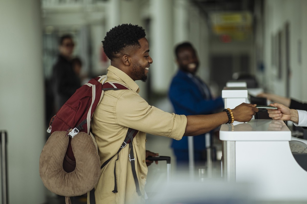 Side view of a young man standing in front of the airport counter