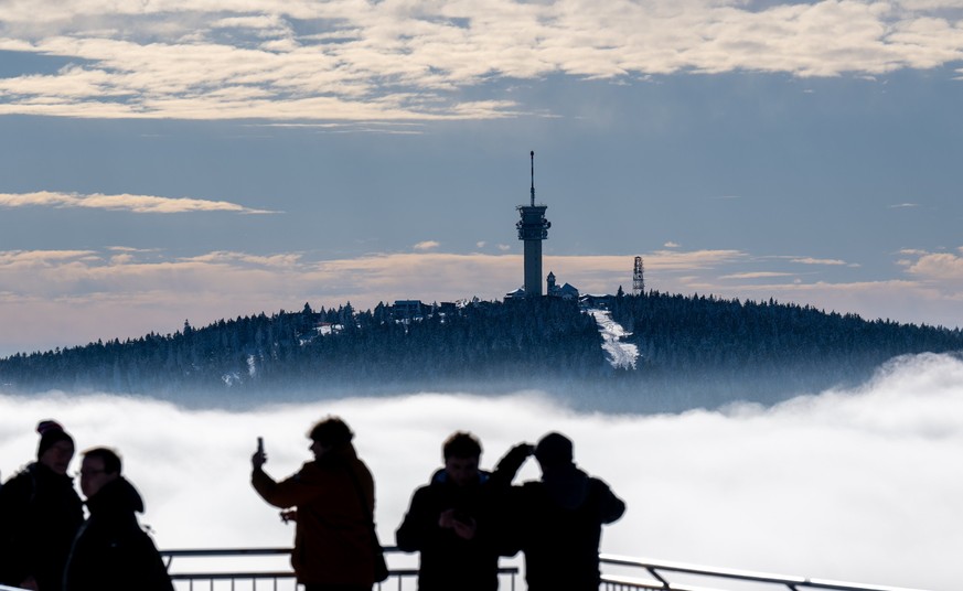 26.01.2023, Sachsen, Oberwiesenthal: Besucher des Fichtelbergs in Oberwiesenthal blicken über die Wolken im Tal hinüber zum 1243 Meter hohen Keilberg auf tschechischer Seite. Eine sogenannte Inversion ...