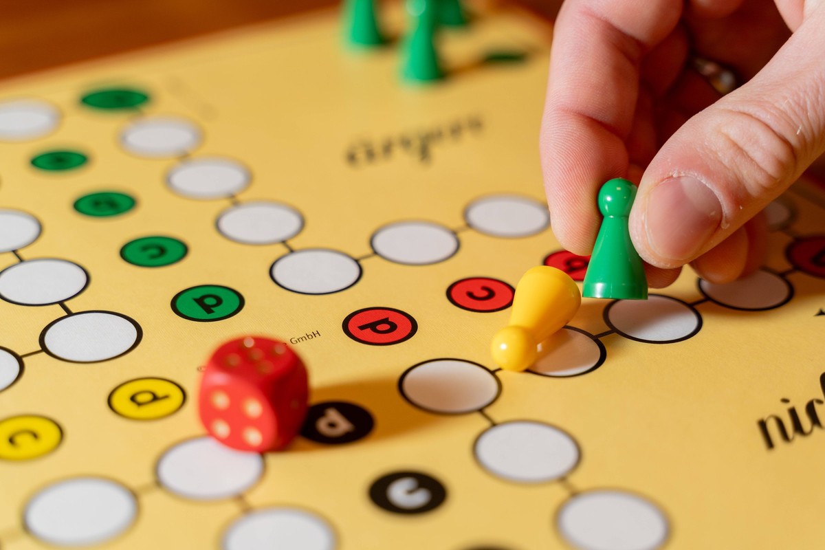 Kammlach, Bavaria, Germany - 1 July 2023: A family plays the board game Mensch ärgere dich nicht. Game board with dice and game pieces *** Eine Familie spielt das Brettspiel Mensch ärgere dich nicht.  ...