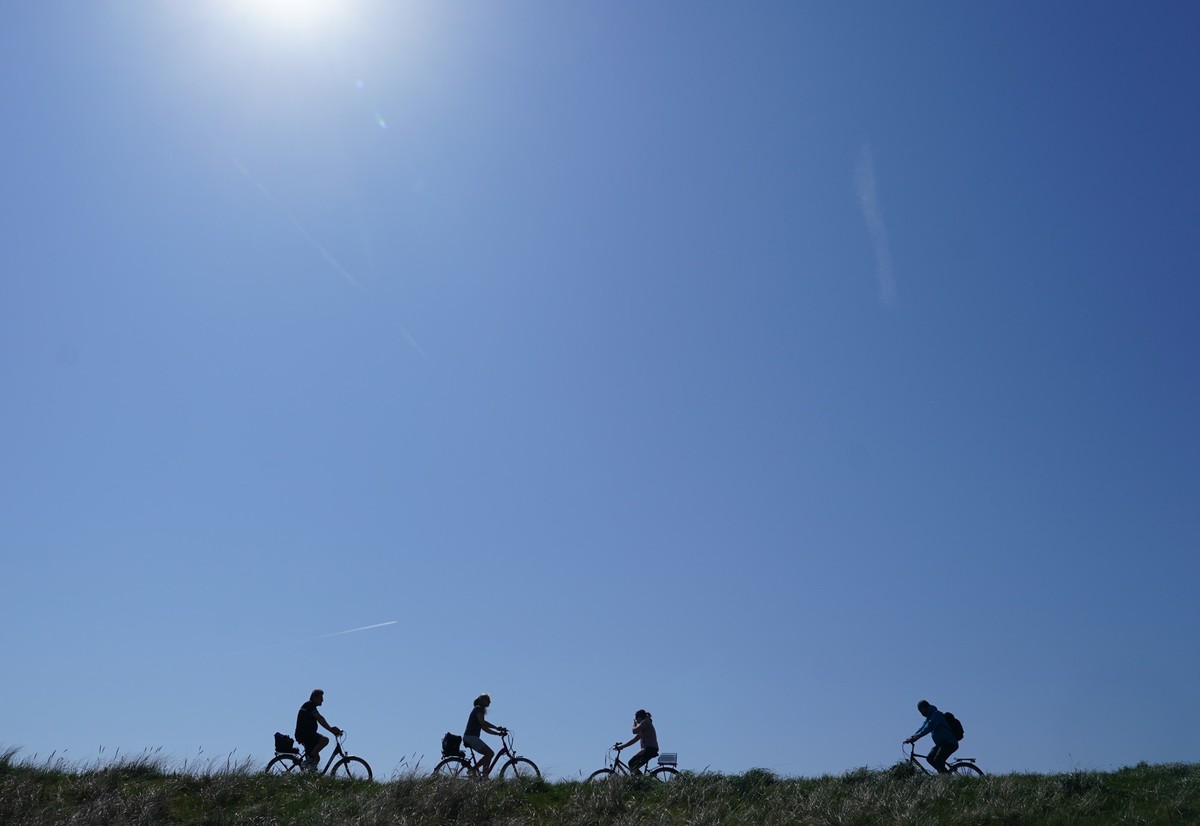 ARCHIV - 02.05.2024, Schleswig-Holstein, St. Peter-Ording: Passanten fahren mit ihren Fahrr�dern auf dem Deich. (zu dpa: �Der Mai im Norden: warm, sonnig und am Ende ziemlich nass�) Foto: Marcus Brand ...