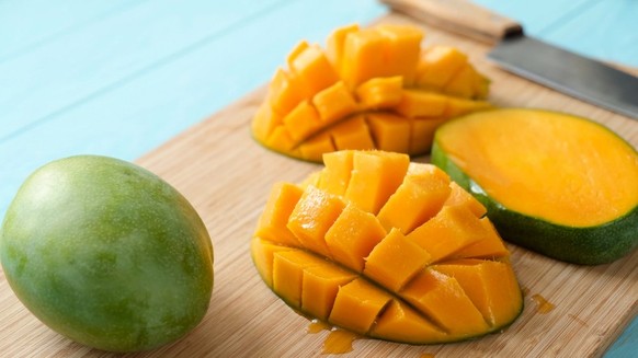 Delicious ripe mango cut in chunks on a wooden cutting board. Tropical fruit juicy mango