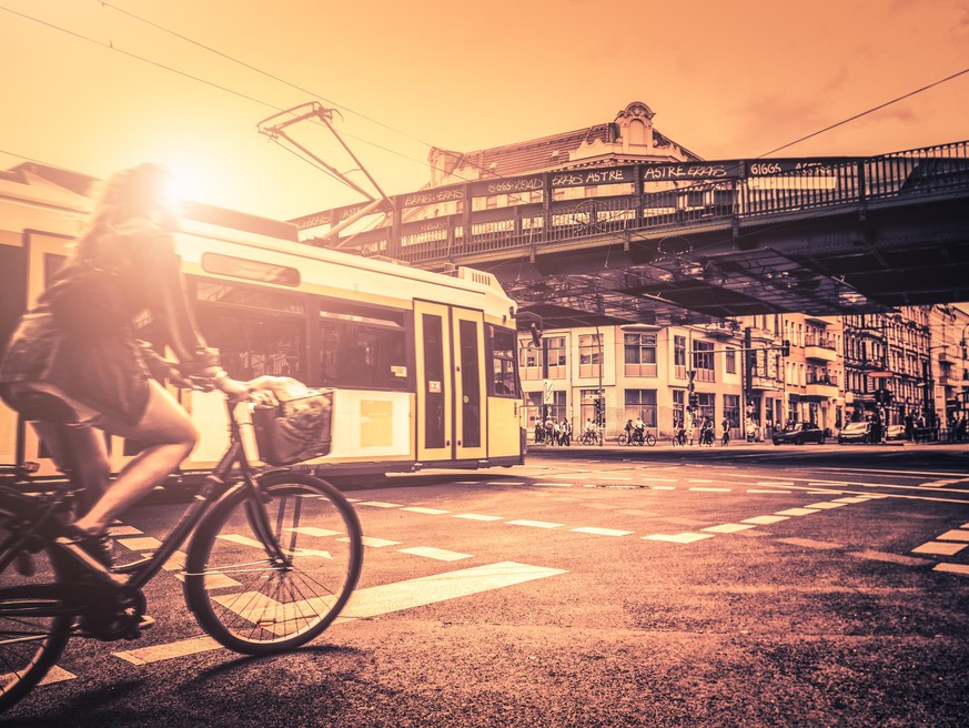 Woman riding a bicycle in Berlin against the tram at sunset. iStockalypse 2012 in Berlin. Little of grain and tilt shift effect added for the mood.