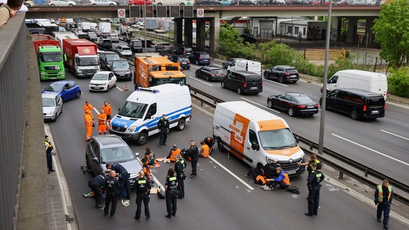 Police officer work to remove glue from the hands of activists of the &quot;Letzte Generation&quot; (Last Generation), who glued themselves to the A100 highway to protest for climate councils, a speed ...