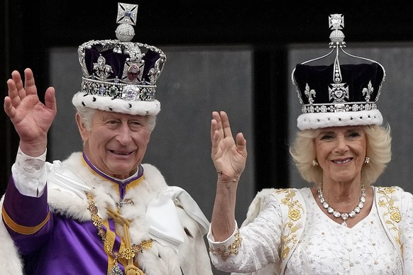 ARCHIV - 06.05.2023, Großbritannien, London: Großbritanniens König Charles III. und Königin Camilla winken nach der Krönungszeremonie der Menge vom Balkon des Buckingham Palace zu. (zu dpa &quot;Ein J ...