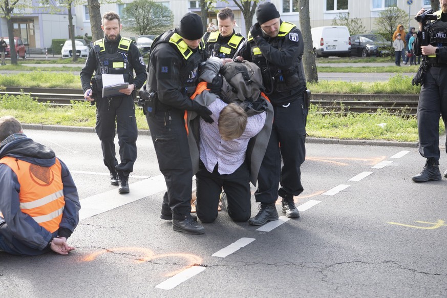 27.04.2023, Berlin: Polizeibeamte nehmen bei einer Blockade der Gruppierung Letzte Generation auf einer Kreuzung an der Landsberger Allee einen Aktivisten vorübergehend fest. Foto: Paul Zinken/dpa +++ ...