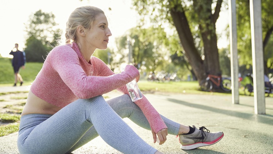 Junge Frau trinkt Wasser, Outdoor-Sport, Olympiapark, München, Deutschland, Europa || Modellfreigabe vorhanden