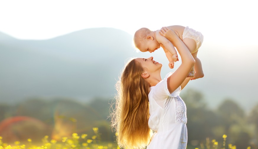 Happy family mother and baby son in a meadow yellow flowers on nature in summer