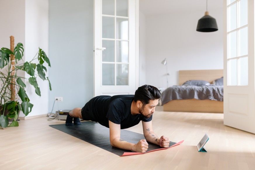 Photo series of a japanese man working out at home, watching youtube videos and learning the exercises.