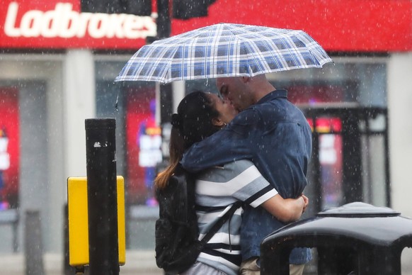 August 17, 2022, London, United Kingdom: A couple seen kissing while sheltering under an umbrella during rainfall in London. London United Kingdom - ZUMAs197 20220817_zab_s197_117 Copyright: xDinendra ...