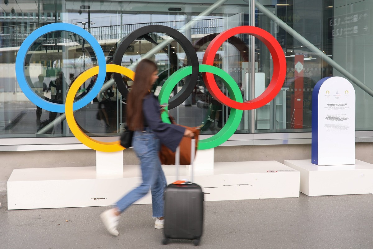 July 11, 2024, Paris, Ile-De-France, France: A young woman tourist walks past the OLYMPIC RINGS outside the terminal building at Paris Orly airport a week ahead of the Paris 2024 Olympic Games, Olympi ...