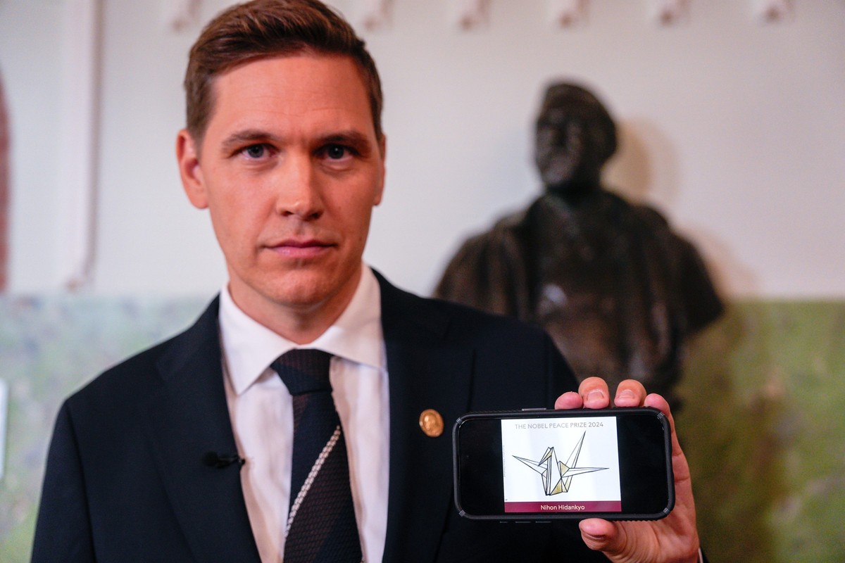 11.10.2024, Norwegen, Oslo: Jorgen Watne Frydnes, der Vorsitzende des Nobelkomitees, präsentiert auf seinem Smartphone das Logo der japanischen Organisation Nihon Hidankyo. Der Friedensnobelpreis geht ...