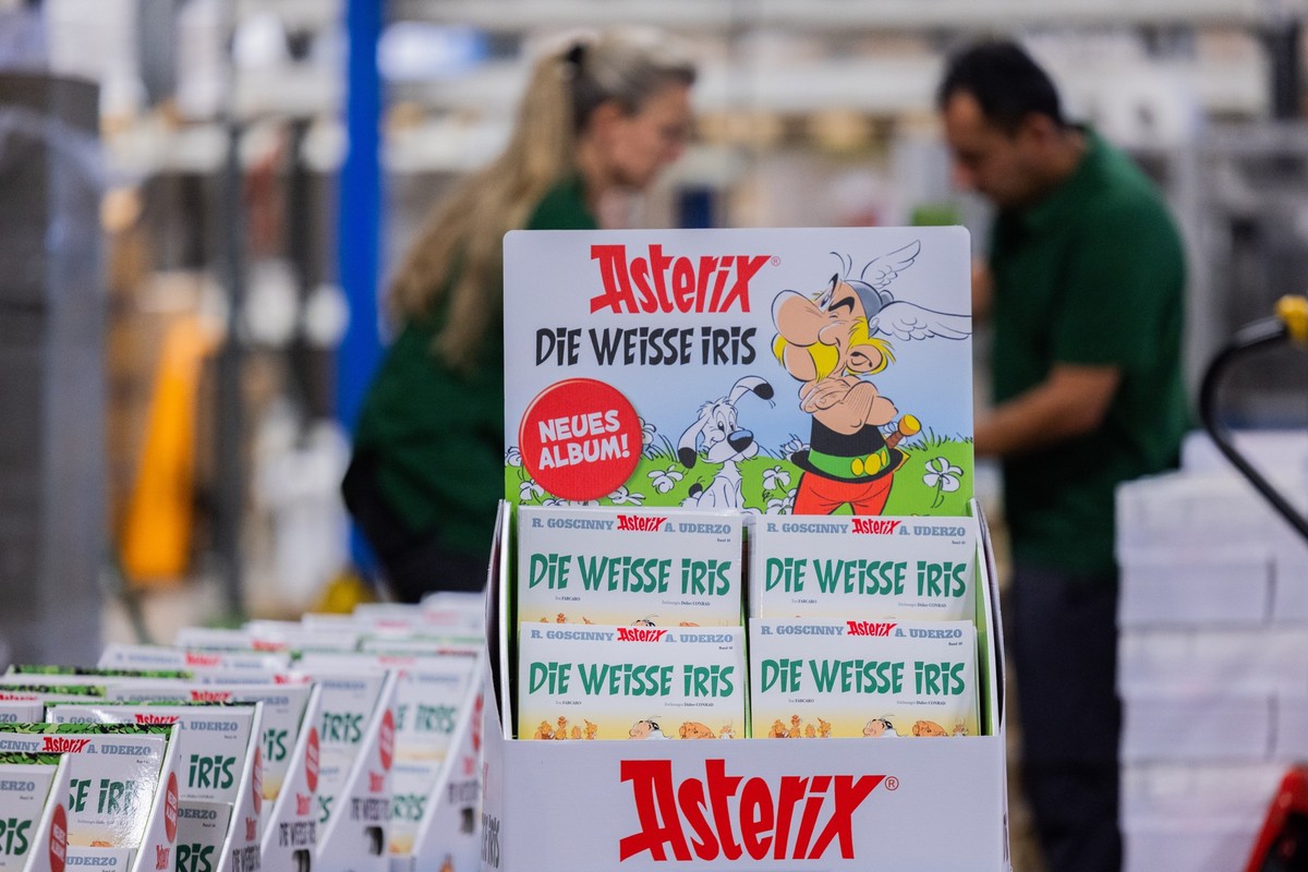 PRODUKTION - 18.09.2023, Nordrhein-Westfalen, K�ln: Ausgaben des neuen Asterix-Band Nummer 40 mit dem Titel &quot;Die wei�e Iris&quot; werden in einer Logistikhalle konfektioniert und in Displays f�r  ...