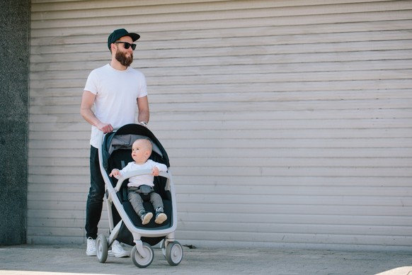 Father walking with a stroller and a baby in the city streets