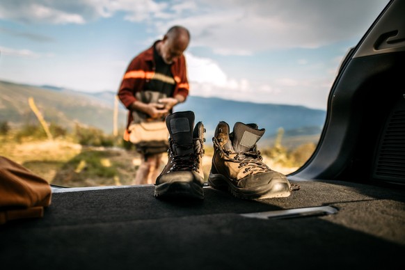 Senior hiker preparing backpack and hiking boots, getting ready for walking