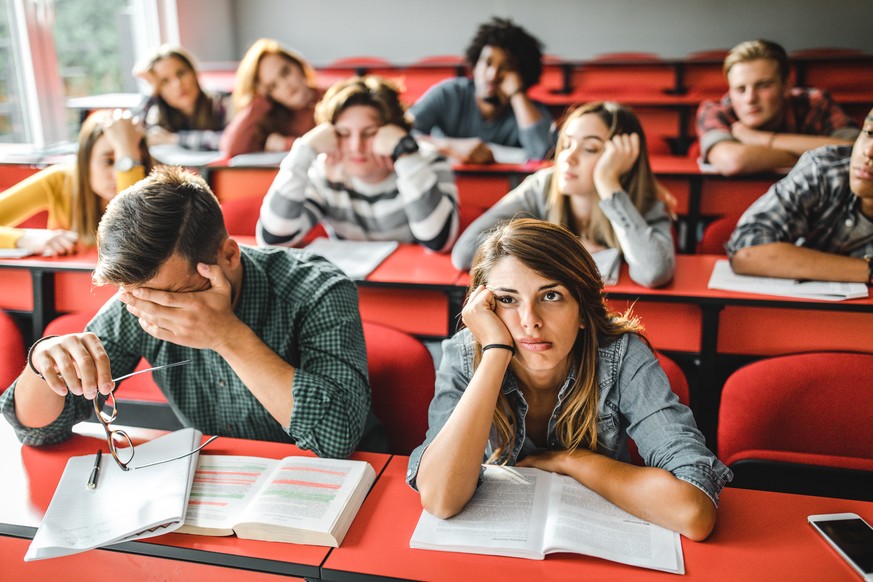 Large group of college students feeling bored on a class at lecture hall.
