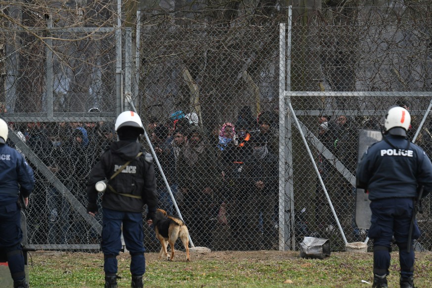 Migrants who want to cross into Greece from Turkey are gathered at the borderline as Greek riot police stand guard, at the closed Kastanies border crossing with Turkey&#039;s Pazarkule, in the region  ...