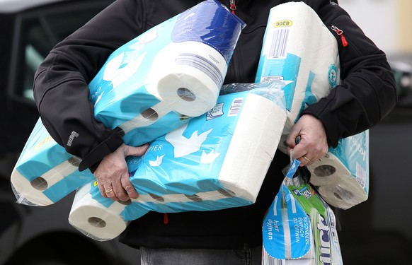 ARCHIV - 18.03.2020, Nordrhein-Westfalen, Siegen: Ein Mann trägt eingekauftes Toilettenpapier und Küchenrollen aus einem Supermarkt. Der Verkauf von Toilettenpapier ist in der vergangenen Woche drasti ...
