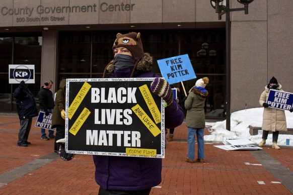 ARCHIV - 18.02.2022, USA, Minneapolis: Ein Demonstrant h�lt ein �Black Lives Matter�-Schild w�hrend eine Gruppe Demonstrierender die Freilassung von Kim Potter auf Bew�hrung fordern. (zu dpa �Adidas s ...