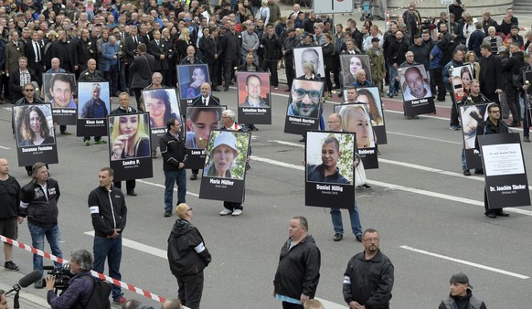 Demonstrators hold photos of people they claim have been killed by migrants during a demonstration in Chemnitz, eastern Germany, Saturday, Sept. 1, 2018, after several nationalist groups called for ma ...