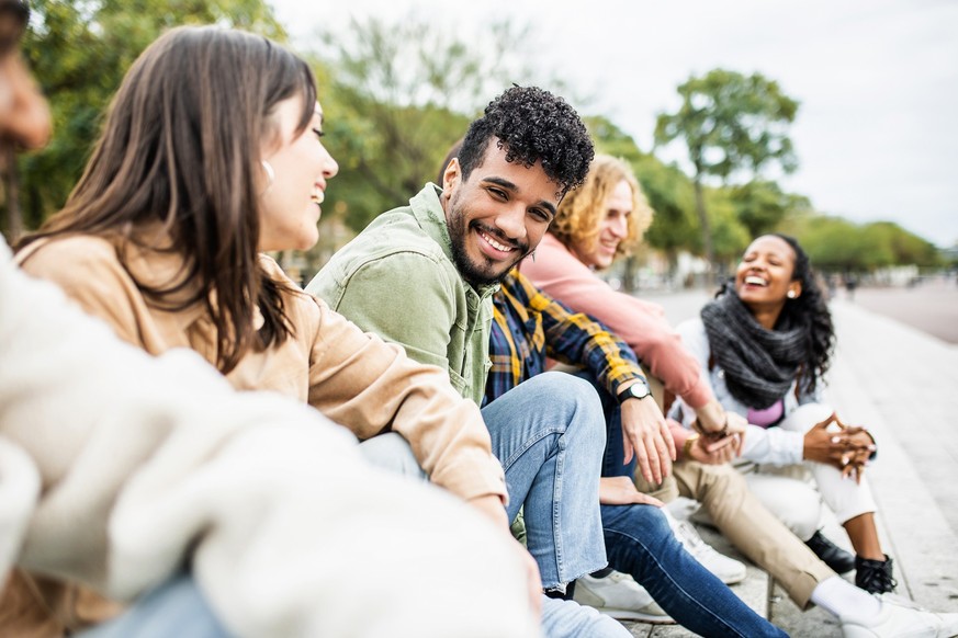 Diverse group of young people laughing together - Hispanic latin man smiling at camera while having fun with multiracial friends in city street - Friendship, unity and millennial colleagues concept