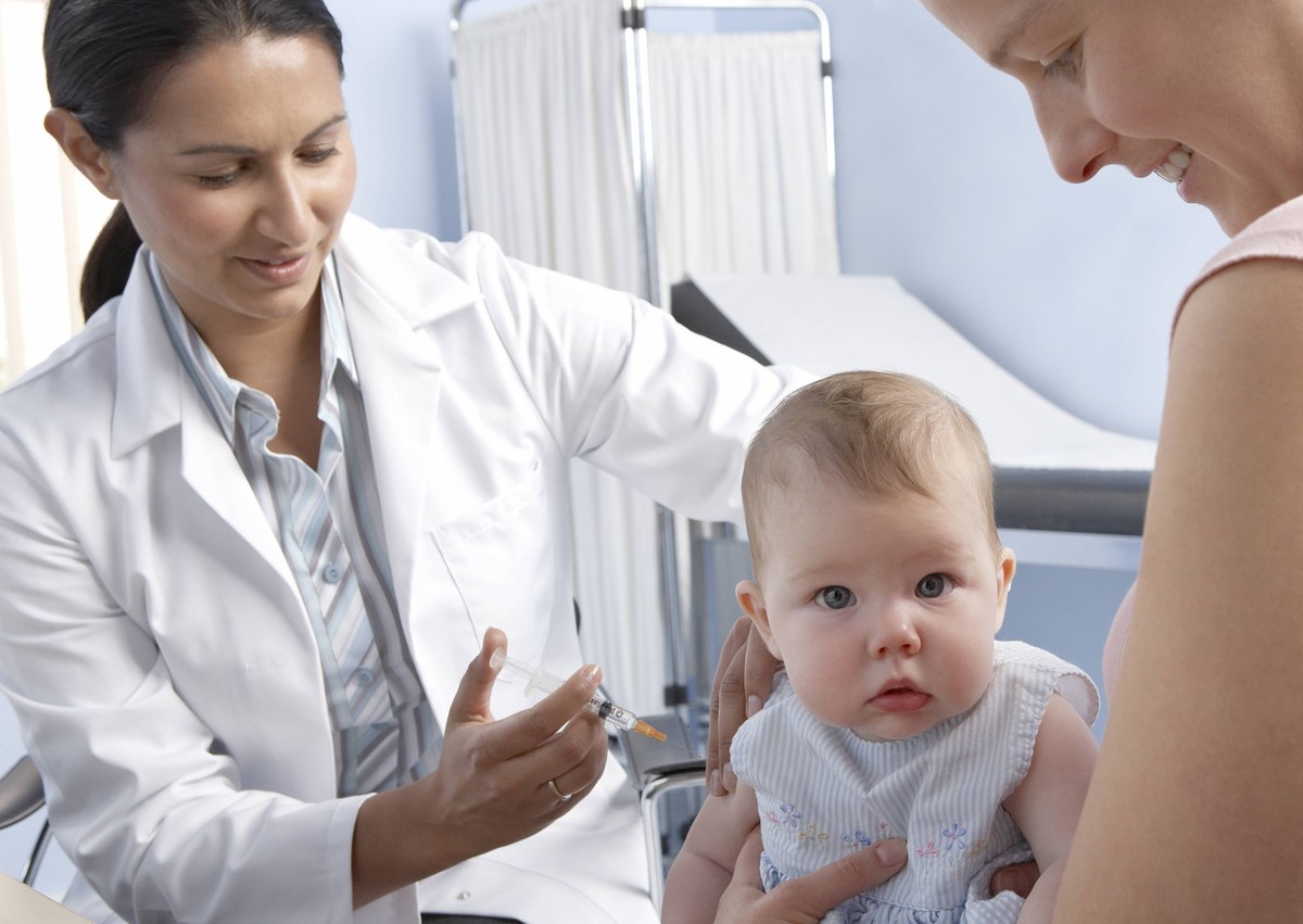 Baby vaccination MODEL RELEASED. Vaccination. 5-month-old baby girl having a vaccine injected into her arm from a syringe. Vaccination provides long-term protection against infectious diseases. The va ...