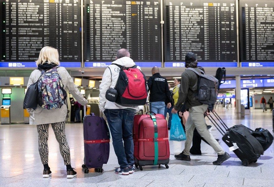 20.02.2024, Hessen, Frankfurt/Main: Passagiere stehen mit ihren Koffern vor der Anzeigetafel im Terminal 1 des Flughafens. Die Gewerkschaft Verdi hat das Lufthansa-Bodenpersonal erneut zu einem Warnst ...