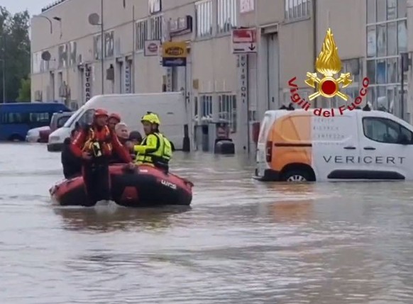 HANDOUT - 19.05.2023, Italien, Ravenna: Das Standbild aus einem Video zeigt Einsatzkräfte der Feuerwehr, die mit einem Schlauchboot Personen aus einem Hotel evakuieren. Nach den dramatischen Überschwe ...