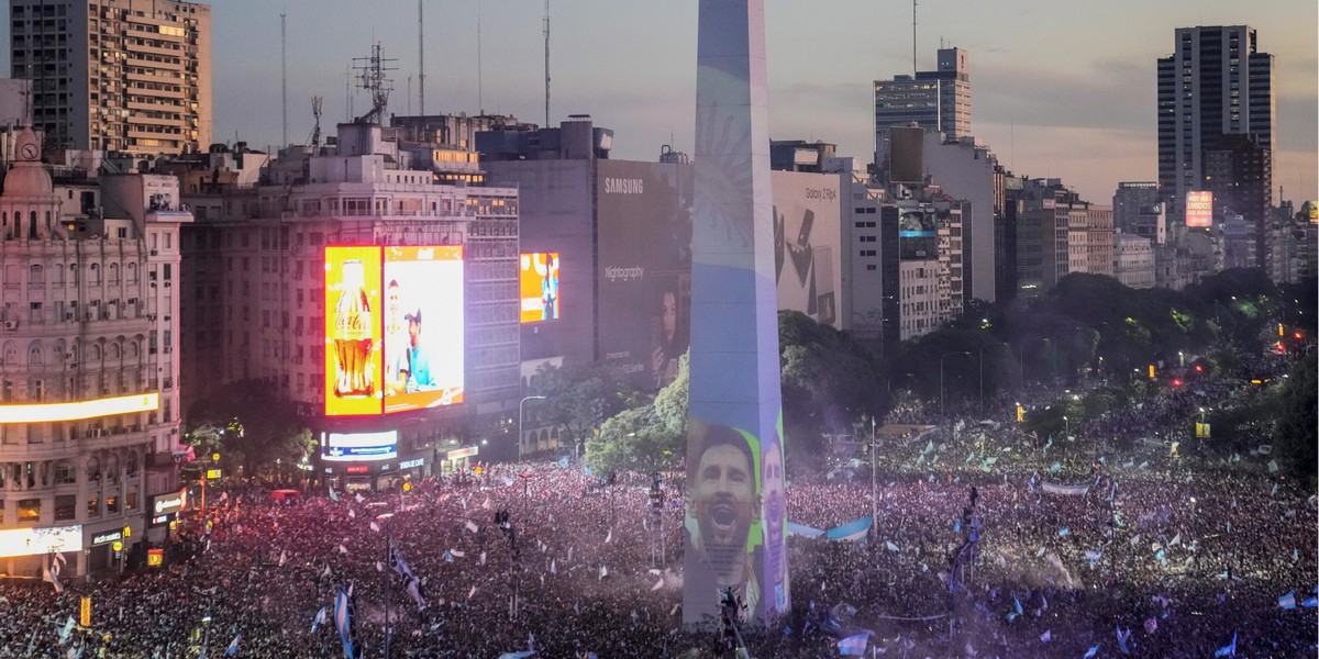 18.12.2022, Argentinien, Buenos Aires: Fu�ball, WM, Argentinien - Frankreich, Finalrunde, Finale: Argentinische Fu�ballfans feiern das Gesicht von Lionel Messi, das auf den Obelisken der Hauptstadt pr ...