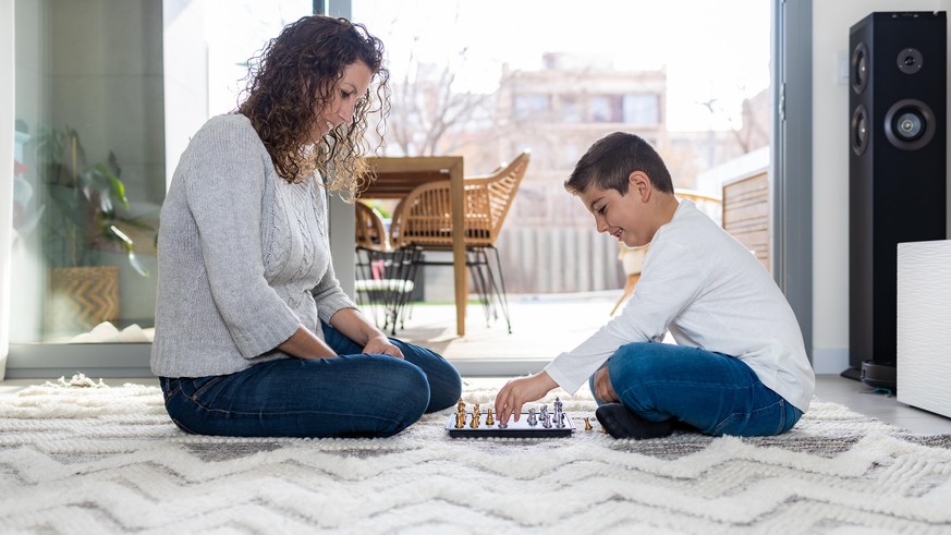 Mother and son playing chess at home