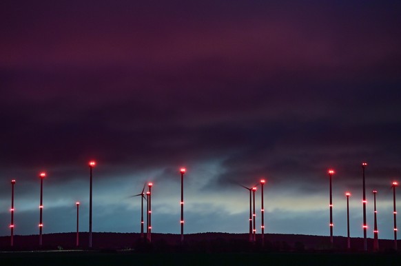 Rote Positionslichter leuchten an Windrädern im Windenergiepark «Odervorland» im Landkreis Oder-Spree.