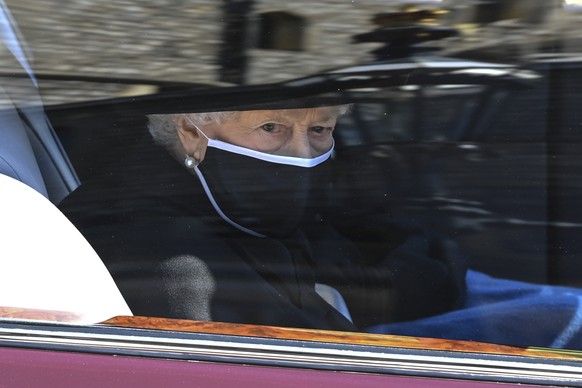 Britain's Queen Elizabeth II follows the coffin in a car as it makes it's way past the Round Tower during the funeral of Britain's Prince Philip inside Windsor Castle in Windsor, England Saturday Apri ...