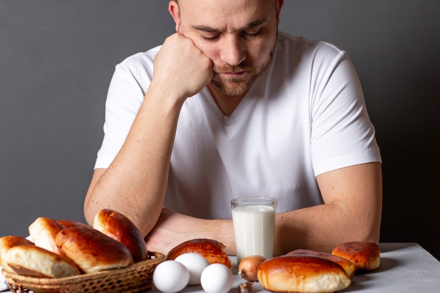 No appetite concept. Portrait of sad upset guy sit table cant eat homemade pies. House weekend