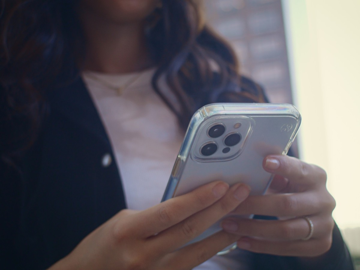 Unknown woman hands holding white modern smartphone on city street close up. Unrecognized girl use phone typing message outdoors. Young lady fingers taken digital gadget with cute ring closeup. xkwx { ...