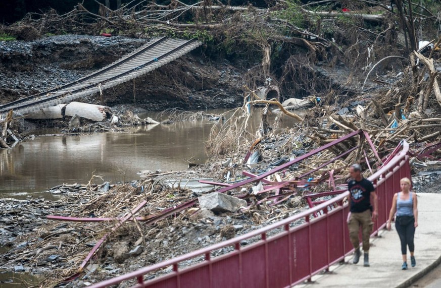 BAD NEUENAHR-AHRWEILER, GERMANY - AUGUST 04: People walk past the Ahr river and destroyed railway tracks by floodwaters during ongoing cleanup efforts in the Ahr Valley region following catastrophic f ...
