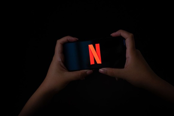 Two hands holding a mobile phone with the logo of Netflix on its screen. (Photo by Nikos Pekiaridis/NurPhoto via Getty Images)