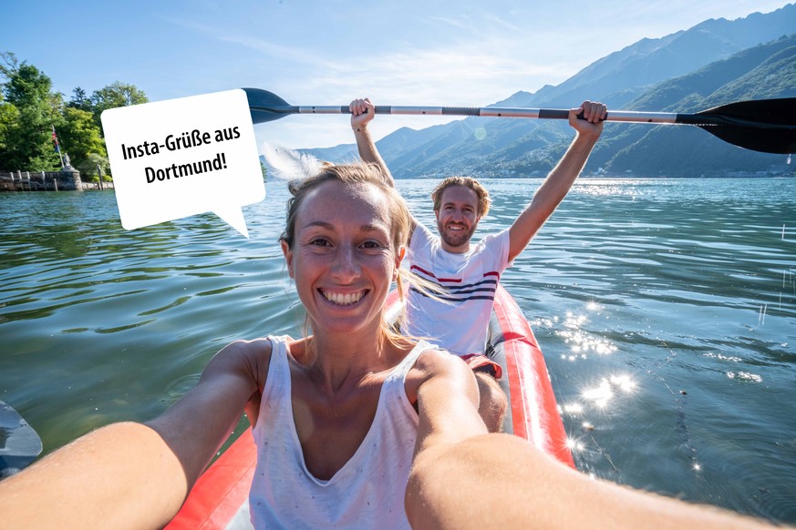 Young couple canoeing take selfie on beautiful mountain lake in Switzerland. Inflatable red canoe on water with mountain sceneryPeople travel outdoor activity concept