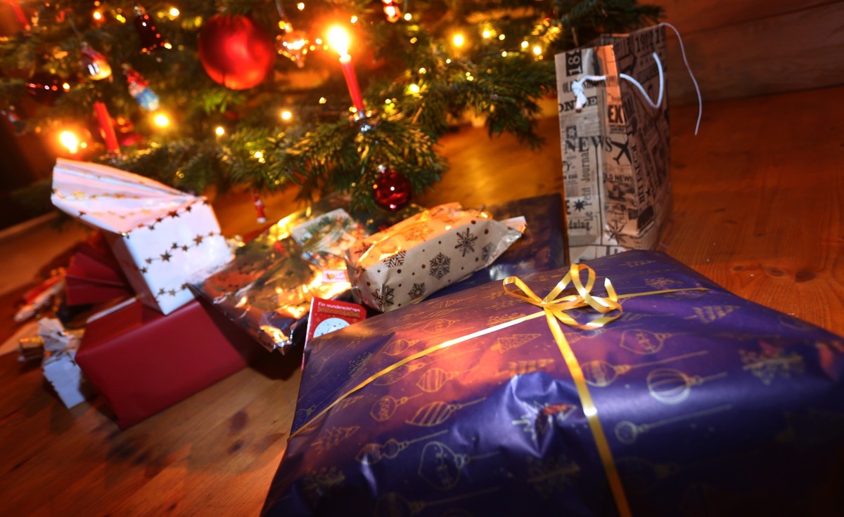 ARCHIV - 24.12.2021, Bayern, Kaufbeuren: Verpackte Geschenke liegen in einem Wohnzimmer unter einem festlich geschm�cktem Weihnachtsbaum. Spielzeug ist ein beliebtes Gut auf Flohm�rkten und Online-Ver ...