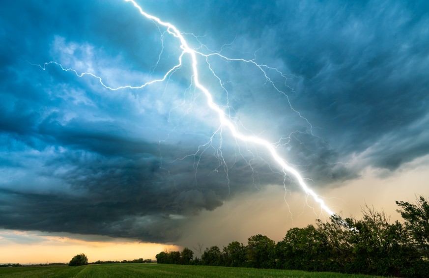 dramatic lightning thundertbolt bolt strike in daylight rural surrounding bad weather dark sky