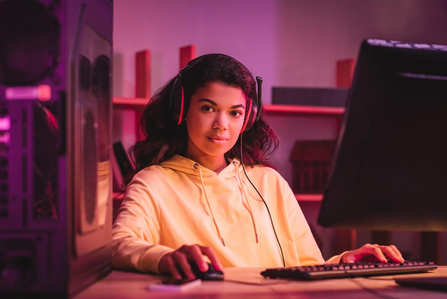 African american gamer in headset looking at camera near computer on blurred foreground