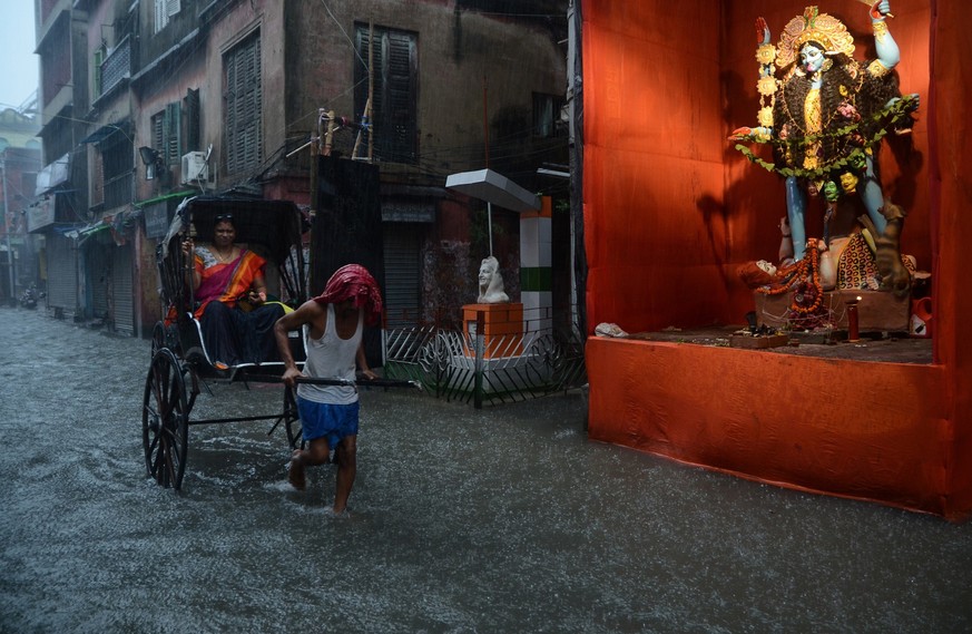 The shot highlights a waterlogged street in Kolkata due to incessant rains from a deep depression in Bay of Bengal, during Kali Puja. As the city battles out the rain and water logging, these hand pul ...
