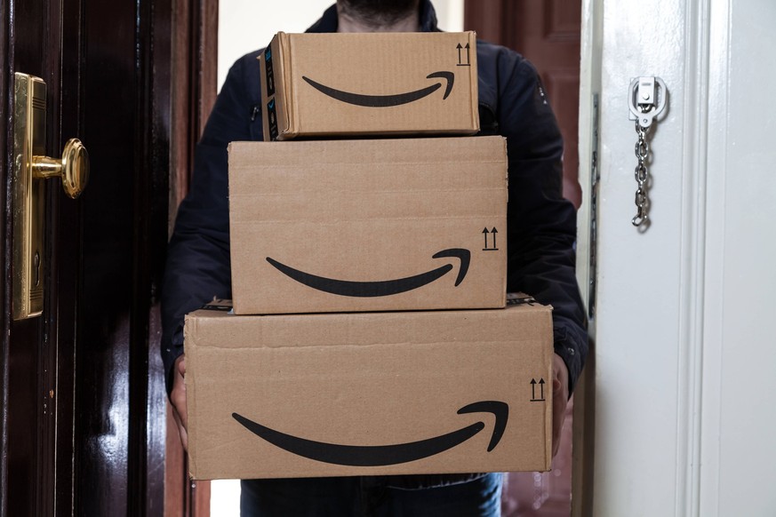 Paketbote liefert drei Amazon Pakete an eine Haustür *** Parcel carrier delivers three Amazon packages to a front door