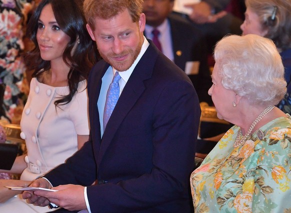 ARCHIV - 26.06.2018, Gro�britannien, London: Die britische K�nigin Elizabeth II. (r-l), der britische Prinz Harry (M)�und dessen Frau Meghan nehmen an den Queen&#039;s Young Leaders Awards teil. (zu d ...